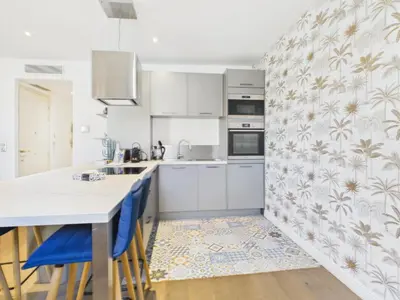 a kitchen with white cabinets and blue bar stools at LE SPECTACULAIRE moderne et raffiné, idéalement situé à deux pas du Palais et plages in Cannes