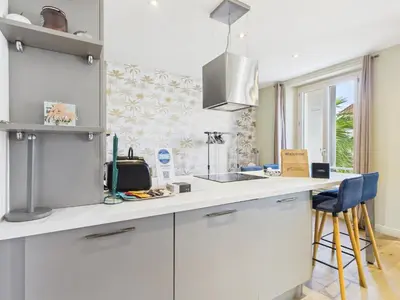 a kitchen with white cabinets and a counter top at LE SPECTACULAIRE moderne et raffiné, idéalement situé à deux pas du Palais et plages in Cannes
