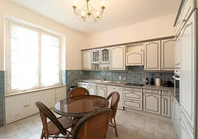 a kitchen with white cabinets and a table and chairs at Viva Riviera Unique Apartment with Terrace and Secret Garden Croisette in Cannes