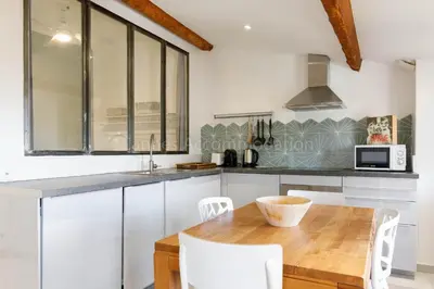 a kitchen with a wooden table and white chairs at Bronze in Cannes
