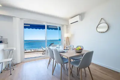a dining room with a table and chairs with a view of the ocean at RARE! 2-Br Seafront Apartment in Cannes