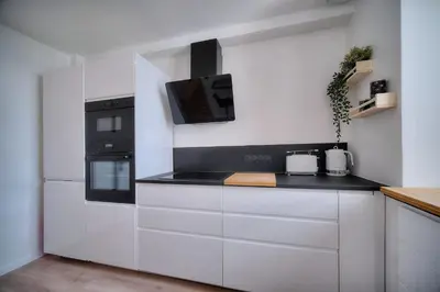 a kitchen with white cabinets and a black stove top oven at IMMOGROOM - Spacious 3-room apartment - Garage - Terrace - Air conditioning in Cannes