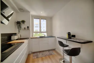 a kitchen with a counter and two stools in it at IMMOGROOM - Spacious 3-room apartment - Garage - Terrace - Air conditioning in Cannes
