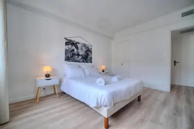 a white bedroom with a large bed and two lamps at IMMOGROOM - Spacious 3-room apartment - Garage - Terrace - Air conditioning in Cannes