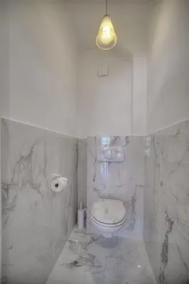 a marble bathroom with a toilet and a light at IMMOGROOM - Spacious 3-room apartment - Garage - Terrace - Air conditioning in Cannes