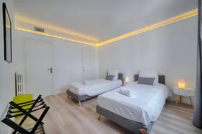 a bedroom with two beds and a chair in it at IMMOGROOM - Spacious 3-room apartment - Garage - Terrace - Air conditioning in Cannes