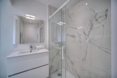 a white bathroom with a shower and a sink at IMMOGROOM - Spacious 3-room apartment - Garage - Terrace - Air conditioning in Cannes