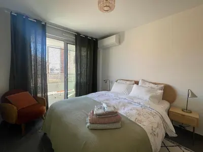 a bedroom with a bed with a chair and a window at Cannes, appartement avec parking+terrasse, Croisette à pied! in Cannes