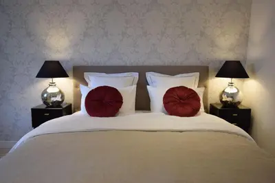 a bed with two red pillows on it with two lamps at Studio Suquet 2 in Cannes