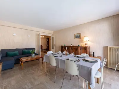 a living room with a table and a blue couch at Apartment Le Valencia by Interhome in Cannes