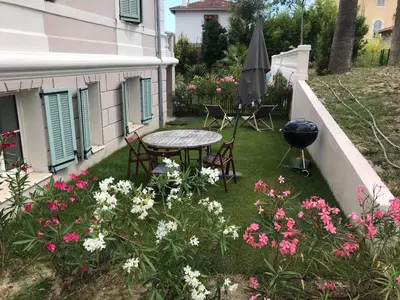 a patio with a table and chairs and flowers at Cannes 2 pieces de 49 m2 ,piscine. Jardin privatif in Cannes
