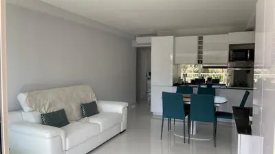 a living room with a white couch and a kitchen at Cannes Pointe Croisette : superbe logement vue mer in Cannes