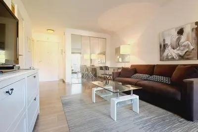 a living room with a couch and a table at Cannes Conseil Immo -Résidence avec piscine, appartement avec terrasse pour 4 personnes in Cannes