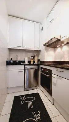 a kitchen with white cabinets and a rug on the floor at Cannes Conseil Immo -Résidence avec piscine, appartement avec terrasse pour 4 personnes in Cannes
