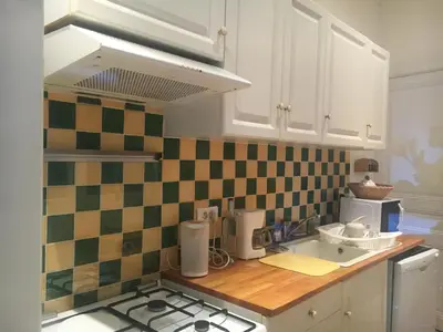 a kitchen with white cabinets and green and white tiles at Maison au calme avec jardin et garage proche du centre et de la mer in Cannes