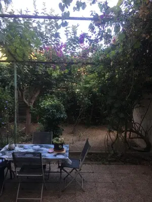 a table and chairs in a garden with a pergola at Maison au calme avec jardin et garage proche du centre et de la mer in Cannes