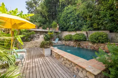 a swimming pool with a wooden deck and an umbrella at Superb villa with swimming pool & sauna in Cannes