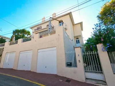 a large house with white doors and a fence at SUPERBE MAISON 6 ch, 4 sdb, terrasses et billard in Cannes