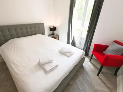 a bedroom with a white bed and a red chair at SUPERBE MAISON 6 ch, 4 sdb, terrasses et billard in Cannes