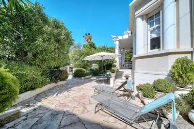 a patio with two chairs and an umbrella at Cannes Luxury Rental - Belle epoque villa to rent close to Cannes center in Cannes