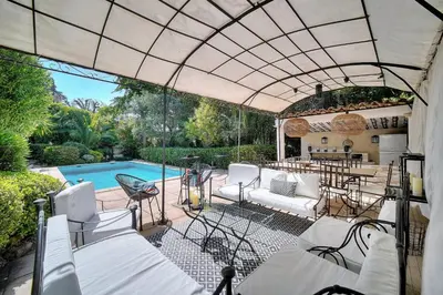 an outdoor patio with white chairs and a swimming pool at Cannes Luxury Rental - Belle epoque villa to rent close to Cannes center in Cannes