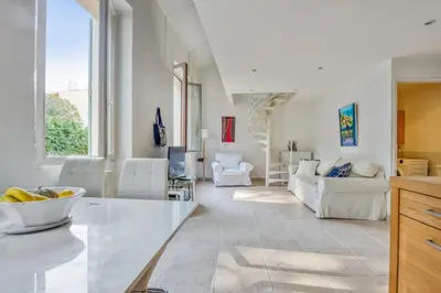 a living room with white furniture and a large window at Appartement Perrissol - Welkeys in Cannes