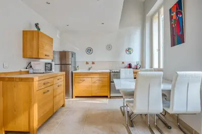 a kitchen with a table and white chairs in it at Appartement Perrissol - Welkeys in Cannes