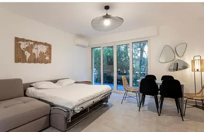 a bedroom with a bed and a couch and a table and chairs at Appart 2 pièces Cannes Croisette-Martinez in Cannes
