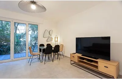 a living room with a television and a table with chairs at Appart 2 pièces Cannes Croisette-Martinez in Cannes