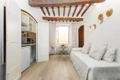 a white living room with a couch and a kitchen at Panisse YourHostHelper in Cannes