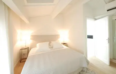 a white bedroom with a white bed with two lamps at FOCH Bright prestigious apartment in Cannes ! in Cannes
