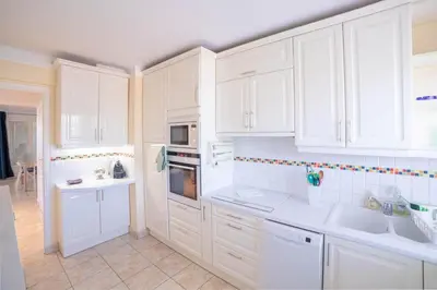 a white kitchen with white cabinets and white appliances at Cannes Elegance – Balcony & Quiet Near Shops in Cannes