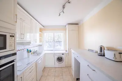 a white kitchen with a washing machine and a window at Cannes Elegance – Balcony & Quiet Near Shops in Cannes