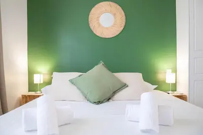 a bedroom with a white bed with a green wall at Cannes Elegance – Balcony & Quiet Near Shops in Cannes