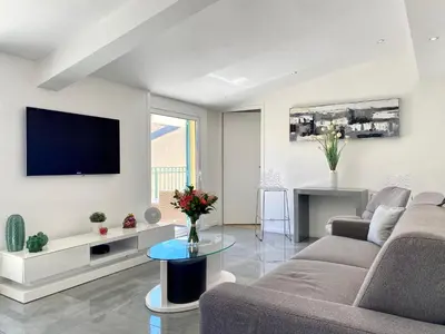 a living room with a couch and a tv on a wall at Duplex Luxury Toîts du Soleil By SCLS Locations in Cannes
