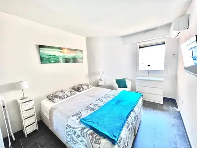 a white bedroom with a bed and a window at VILLA MAUPASSANT BORD DE MER in Cannes