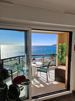 a room with a balcony with a view of the ocean at VILLA MAUPASSANT BORD DE MER in Cannes