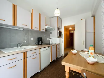 a kitchen with white cabinets and a wooden table at Apartment Le Morélia by Interhome in Cannes