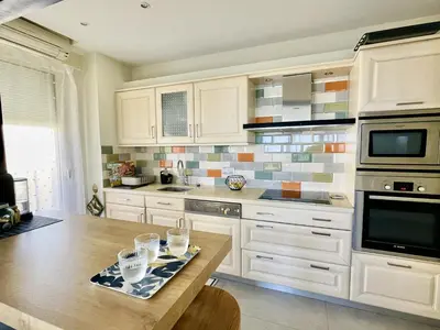 a kitchen with white cabinets and a wooden table at Bella vista luxe 2 chambres in Cannes