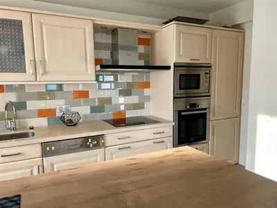 a kitchen with white cabinets and a wooden counter top at Bella vista luxe 2 chambres in Cannes