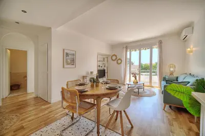 a living room with a table and chairs and a couch at Le Joy - Terrasse - Parking - Verrière Côte d'Azur in Cannes