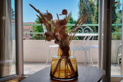 a vase filled with flowers sitting on a table at Le Joy - Terrasse - Parking - Verrière Côte d'Azur in Cannes