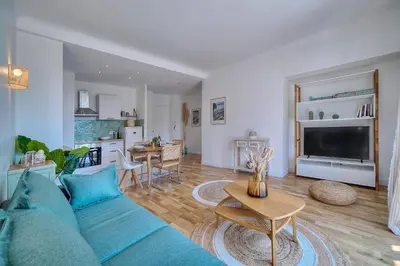 a living room with a blue couch and a kitchen at Le Joy - Terrasse - Parking - Verrière Côte d'Azur in Cannes