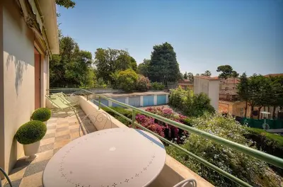 a balcony with a table and chairs and flowers at Le Joy - Terrasse - Parking - Verrière Côte d'Azur in Cannes