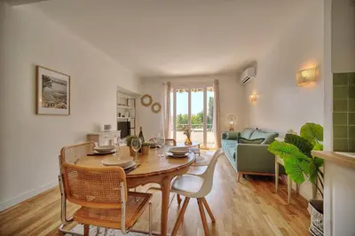 a kitchen and living room with a table and chairs at Le Joy - Terrasse - Parking - Verrière Côte d'Azur in Cannes