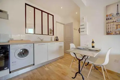 a kitchen with a washing machine and a table with chairs at Le Max et Leo - 600m plage - Verrière côte d'Azur in Cannes