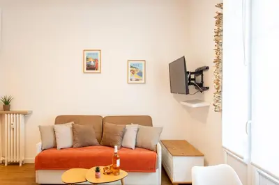 a living room with a couch and a tv at Studio Blvd Carnot 10 min Palais Festivals - Balcony & AC in Cannes
