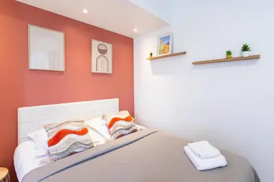 a bedroom with red walls and a bed with pillows at Studio Blvd Carnot 10 min Palais Festivals - Balcony & AC in Cannes