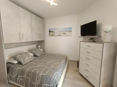 a bedroom with a bed and a dresser with a tv at Coquet 2 pièces entièrement rénové et climatisé in Cannes