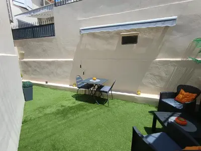 a patio with a table and chairs on grass at Coquet 2 pièces entièrement rénové et climatisé in Cannes